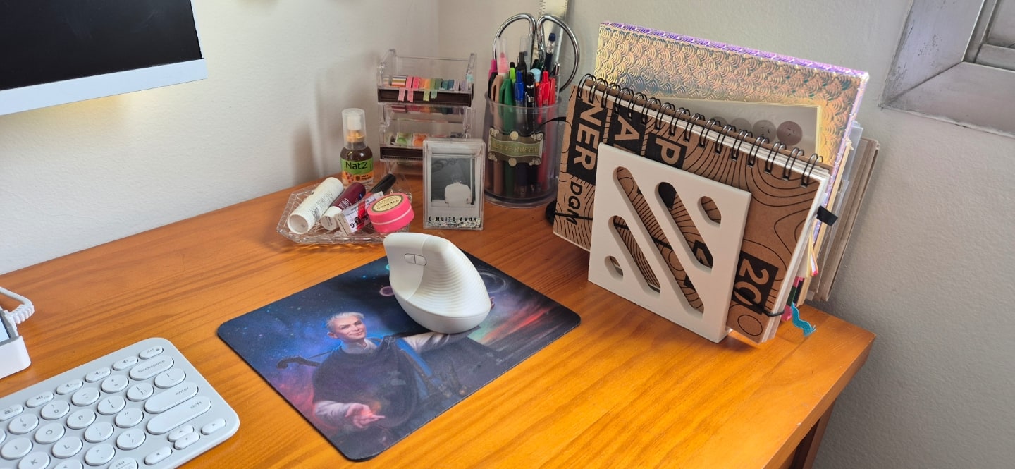Detalhe do mouse, mousepad e alguns cadernos na vertical, em um organizador.