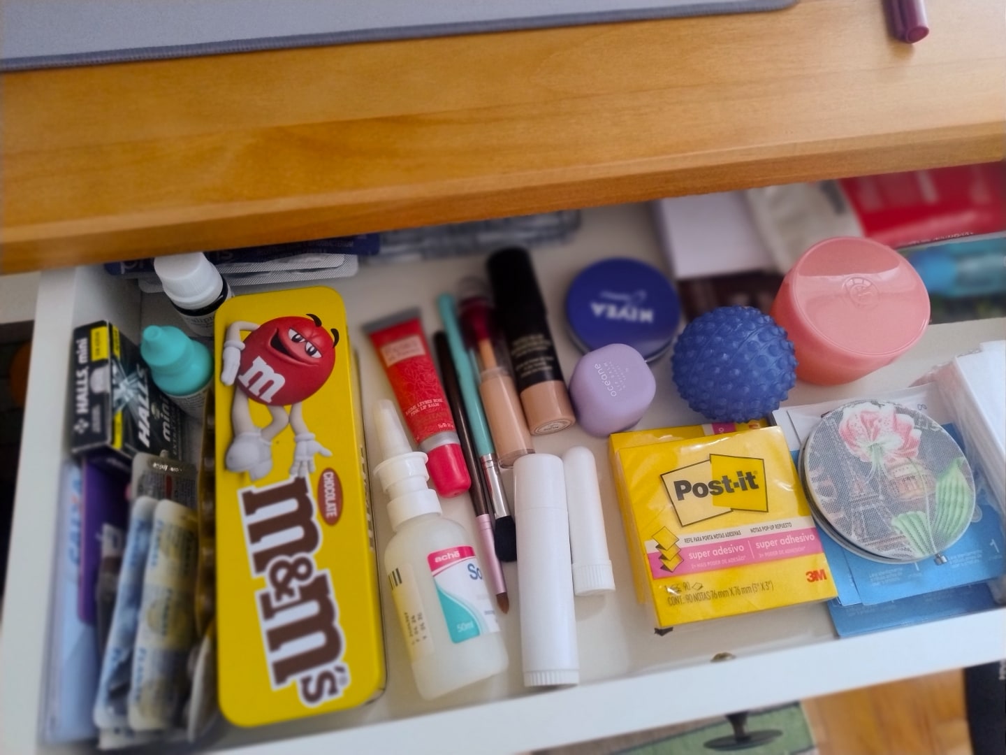 Outra gaveta com esmaltes, M&Ms, post-its, colírio e outros itens pequenos.