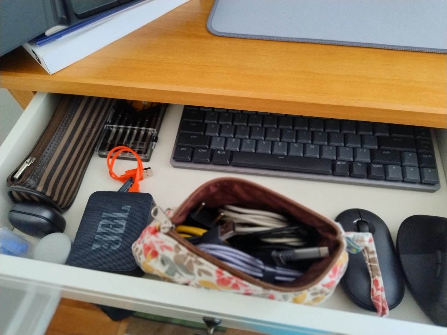 Gaveta aberta com cabos e acessórios de computadores.