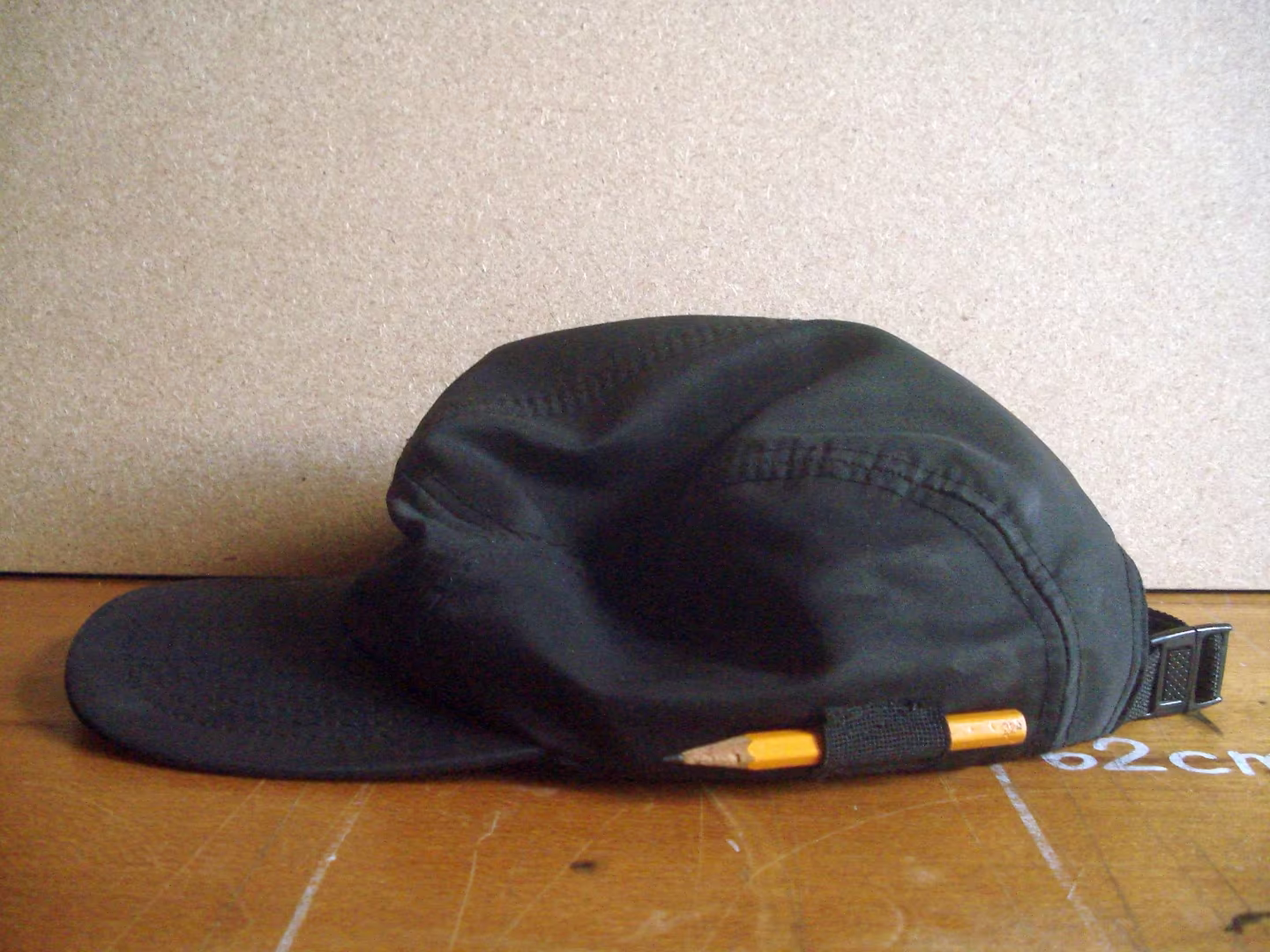 Foto lateral do boné com um lápis enfiado em um apoio costurado ao boné.