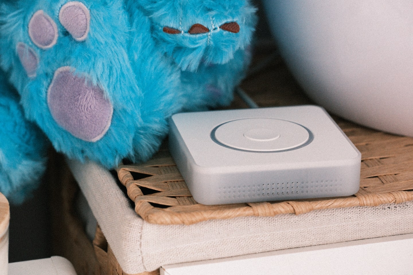 The Home Assistant Voice PE, a white box with a dial on top, next to a blue plush doll.