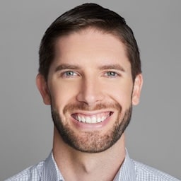 Homem branco, com barba por fazer e sorrindo.