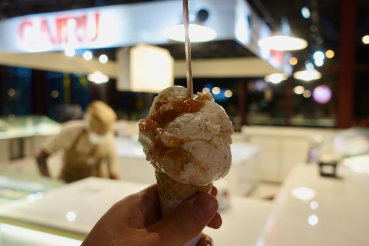 Photo of a scoop of carimbó ice cream in front of Cairu's storefront.