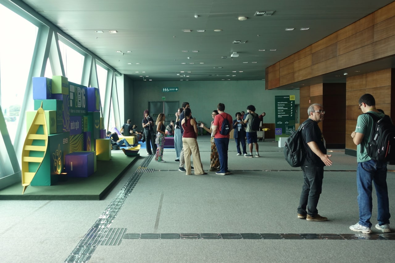 Overview of the wide corridor, with people scattered throughout and a photo panel to the left, in front of large windows.