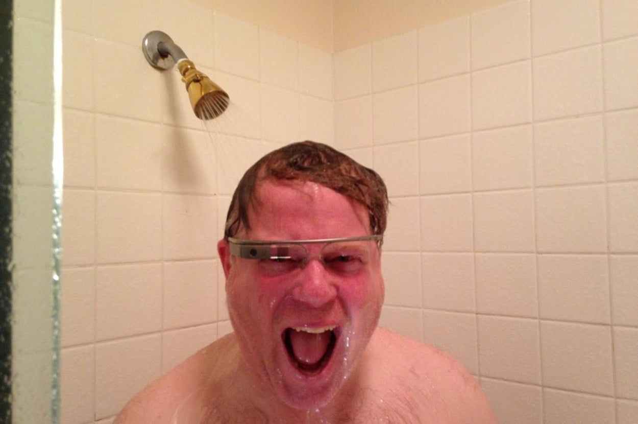 Homem loiro, com a boca aberta e usando Google Glass, embaixo de um chuveiro.