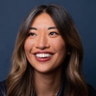 Mulher com traços asiáticos e cabelo escuro longo e liso, sorrindo.